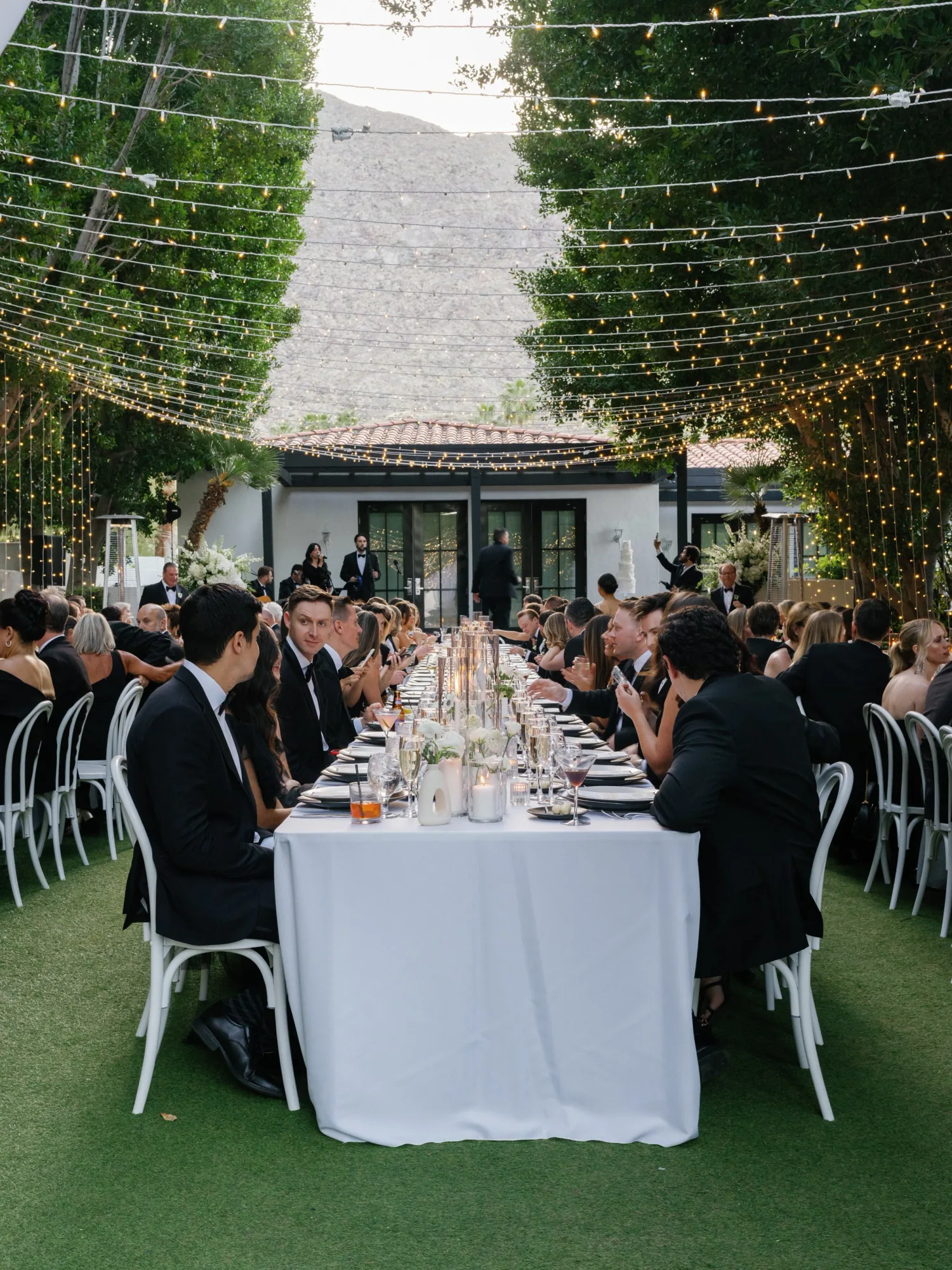 Guests seated at a long dinner table in the garden.
