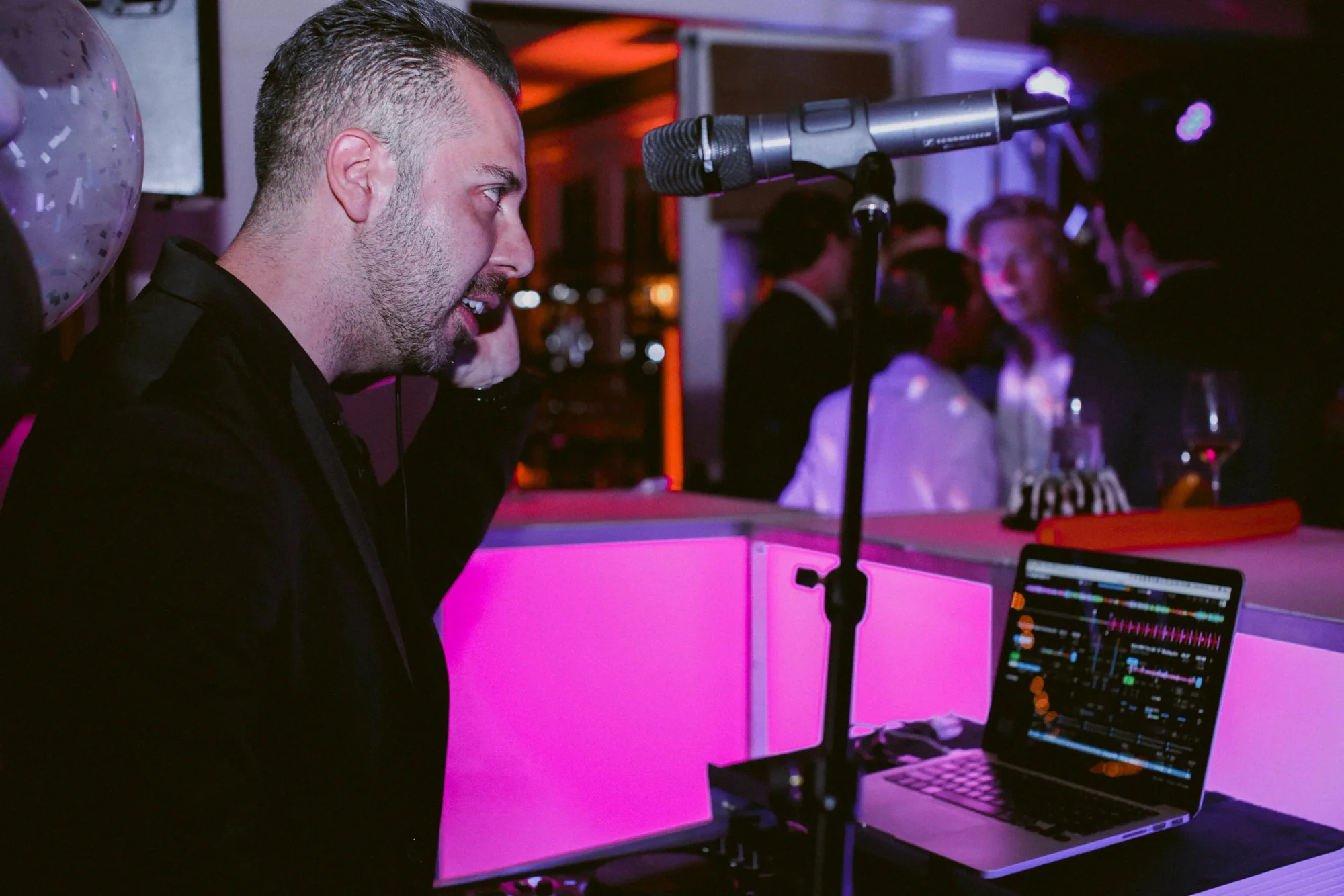 A DJ Live performer singing beside the DJ booth.