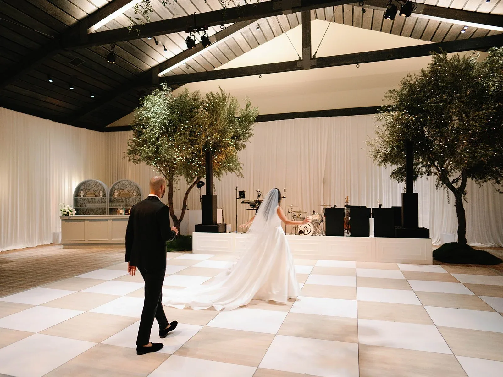 The couple entering a reception room with a patterned dance floor.