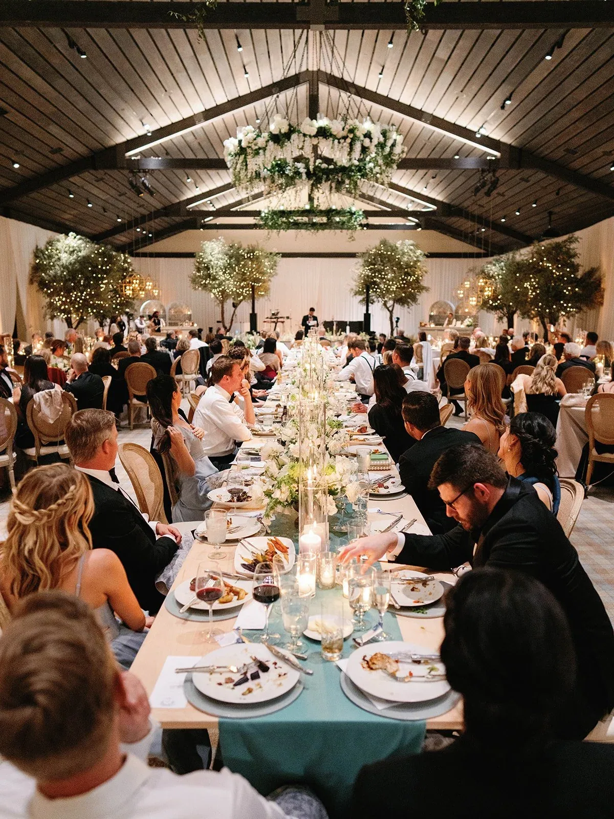 A candlelit dinner set beneath the timber roof of the reception space.