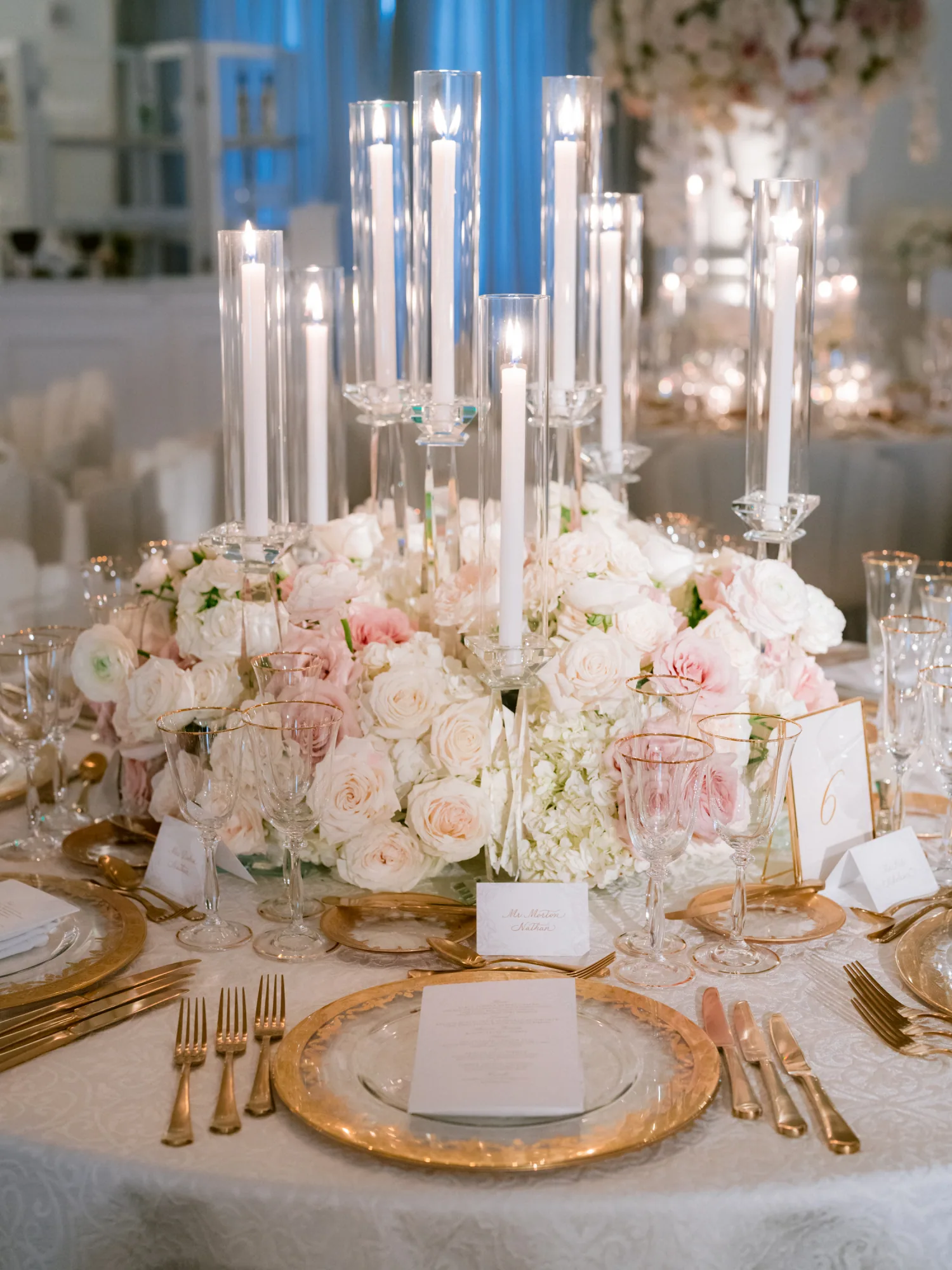 A candlelit reception table with pale floral arrangements.