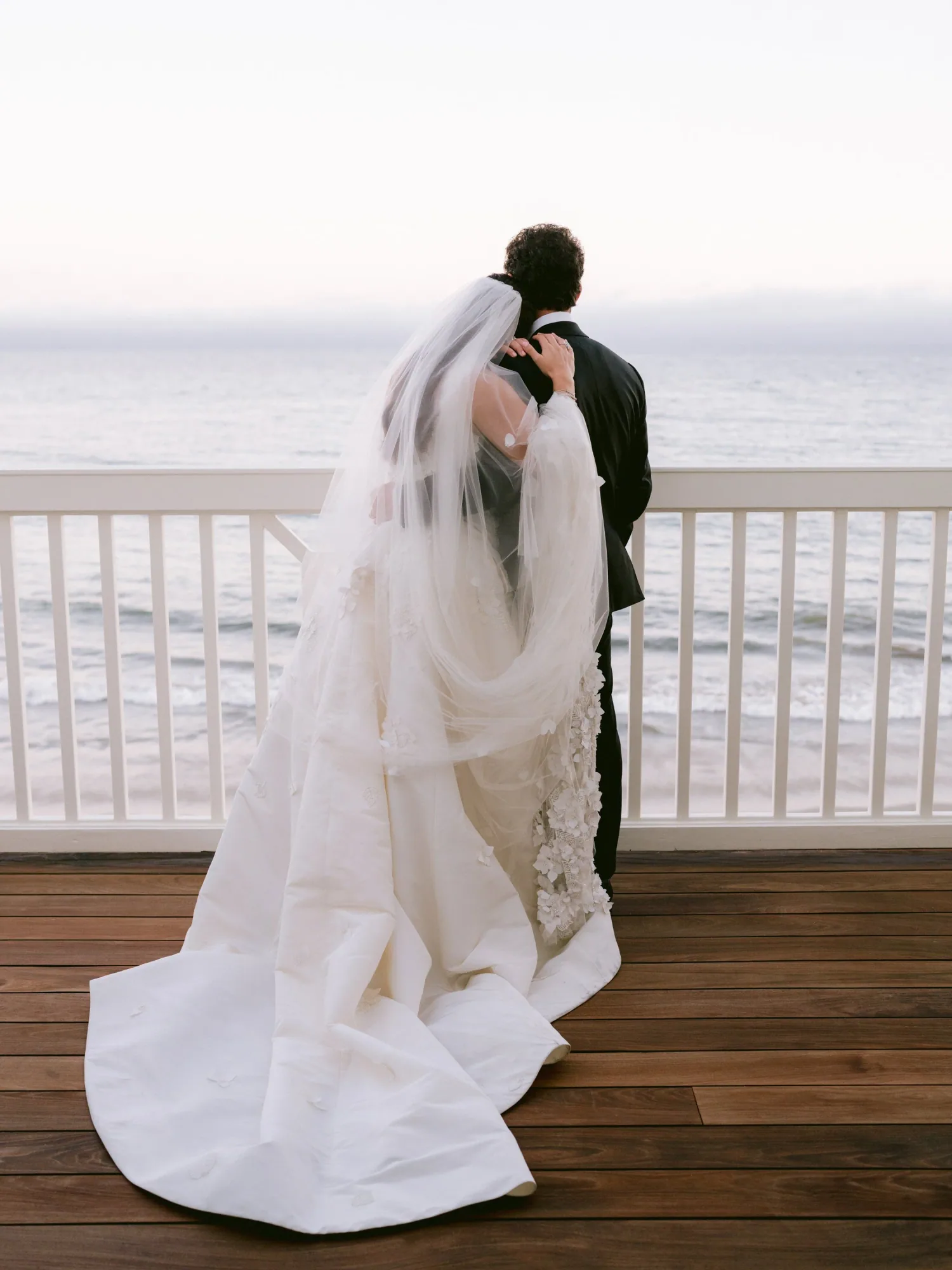 The couple standing together on a terrace overlooking the Pacific.