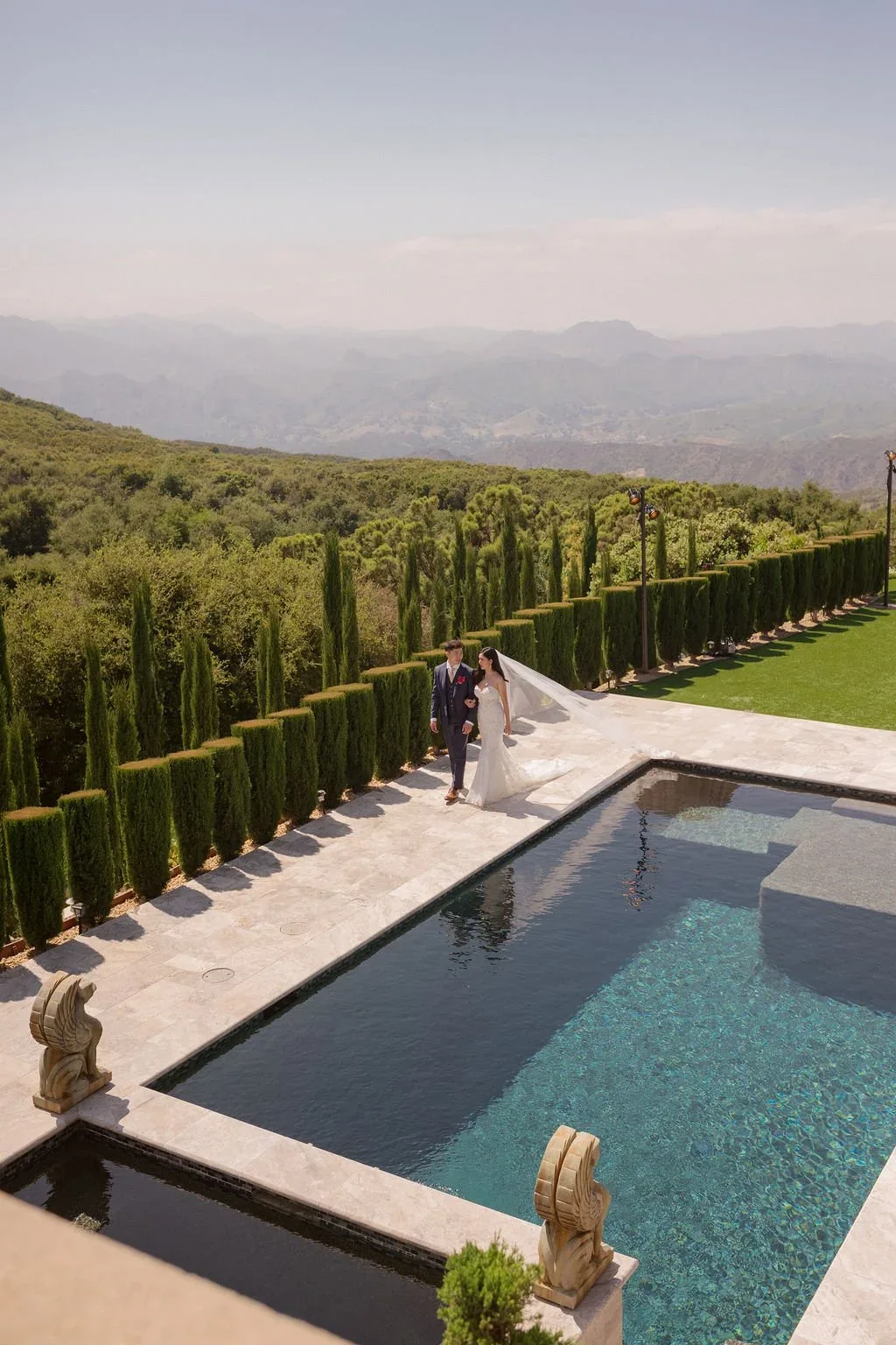 The couple beside the estate pool and sculpted gardens.