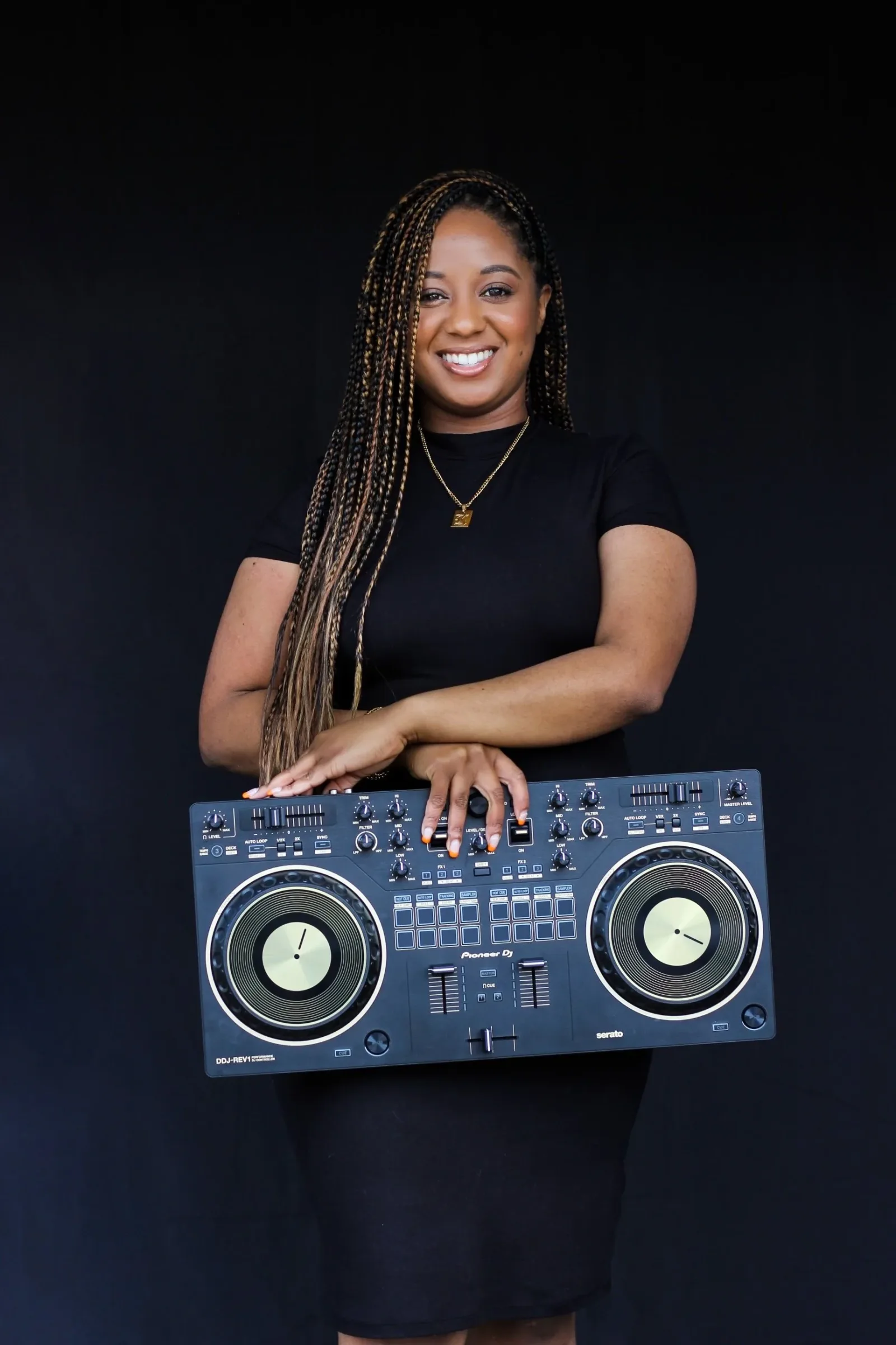 DJ Kasey holding a DJ controller in a studio portrait.