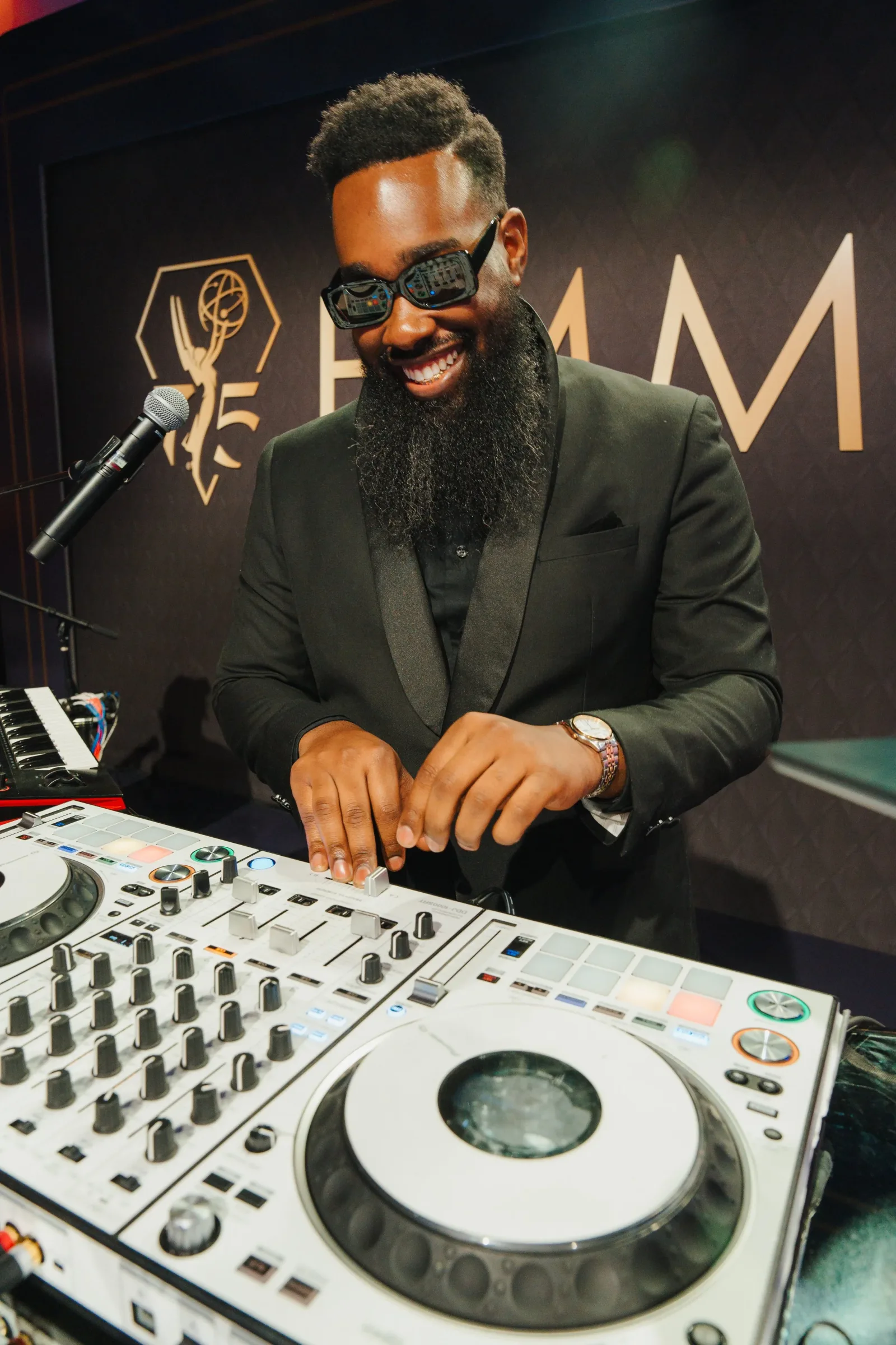 DJ V smiling while performing behind the decks.